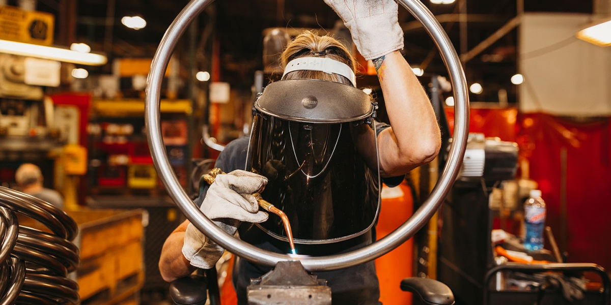 female BioFit welder looking through a steel footring as she welds it
